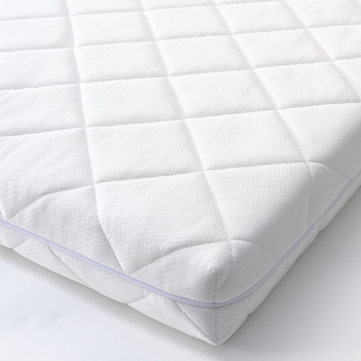 Matelas bébé blanc à housse matelassée et respirante, conçu pour offrir un soutien ferme et confortable