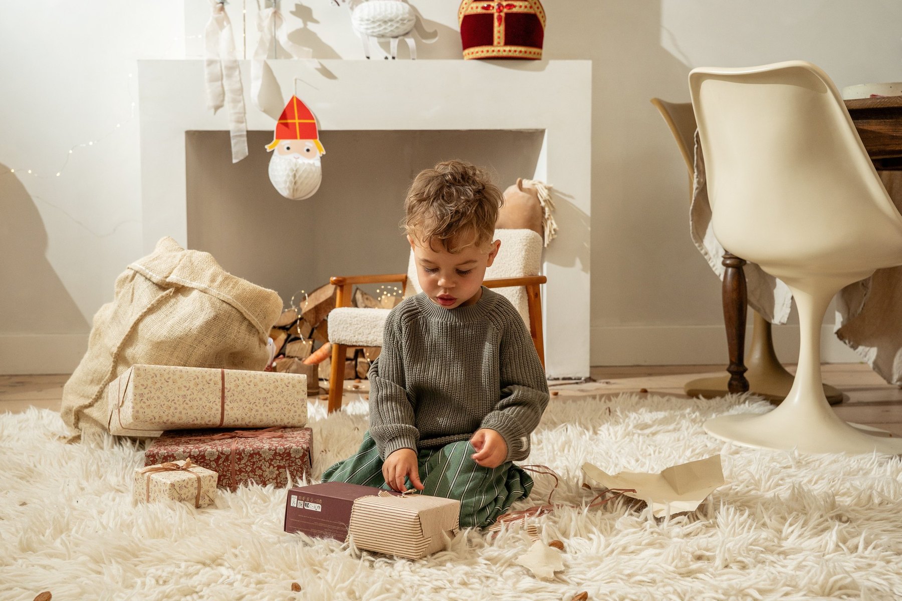 Jongen pakt zijn cadeau uit bij de haard